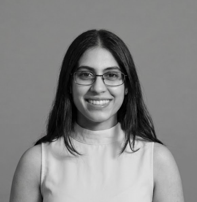 A black and white headshot of Shriya Gurkha, wearing a sleeveless light-colored top and smiling into the camera, set against a plain gray background.